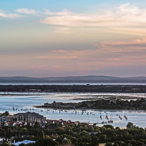 A view over Portchester Castle to the Isle of Wight at sunset