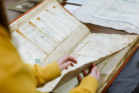 A pair of hands flicking through a historical archive