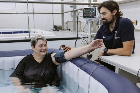 Study participant immersed in a hot tub while Dr Thomas James checks her blood pressure