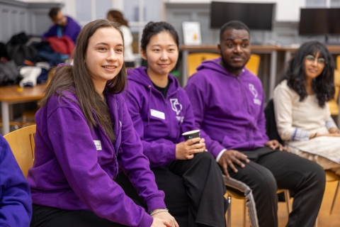 Students sitting together in purple university hoodies