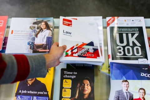 Career guidance books and leaflets on a desk with a person's hand picking one up