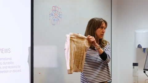 A student presenting her research and holding up a children's t shirt that she has printed on