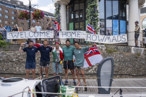 A team of five rowers celebrating on land after rowing around Great Britain