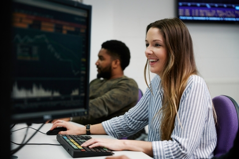 Woman smiling at computer using financial technology.