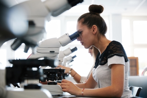 Female student using microscope