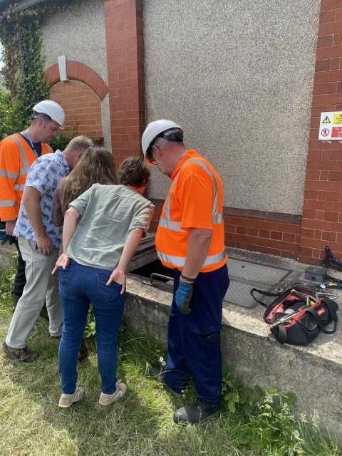 A group of individuals wearing orange vests and hard hats, engaged in a construction or safety-related activity.