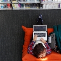 Aerial view of a person sitting on an orange sofa using a laptop