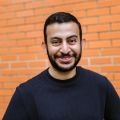 Headshot of male student stood in front of orange brick wall