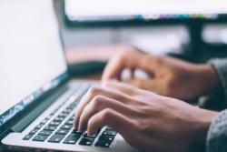 Hands typing on a laptop