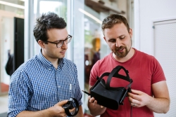 A staff member explaining to another staff member how a VR headset works