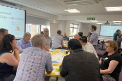 Several individuals seated at a table in a room, participating in a collaborative discussion