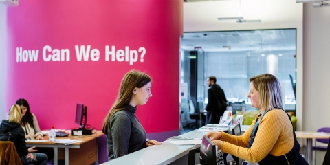 Female student standing at careers and employability help desk