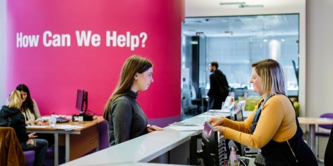 Female student standing at careers and employability help desk