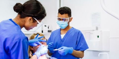 Two dental students work on patient