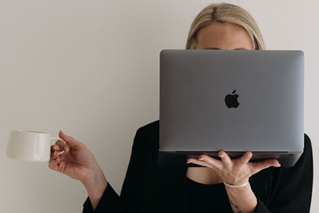 Graduate, Natty, holding a mug with a hot drink and a gret laptop