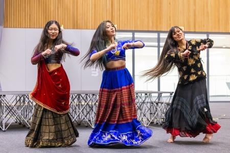 Three people dancing in traditional dress of their culture at One World Festival 