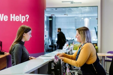 Female student standing at careers and employability help desk
